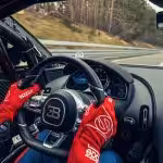 Vodič v pretekárskych rukaviciach drží volant športového vozidla Bugatti Chiron