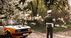 Príslušník Verenej bezpečnosti stojí pred motorovým vozidlom značky Škoda