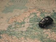 malý model autíčka položený na mape Európy