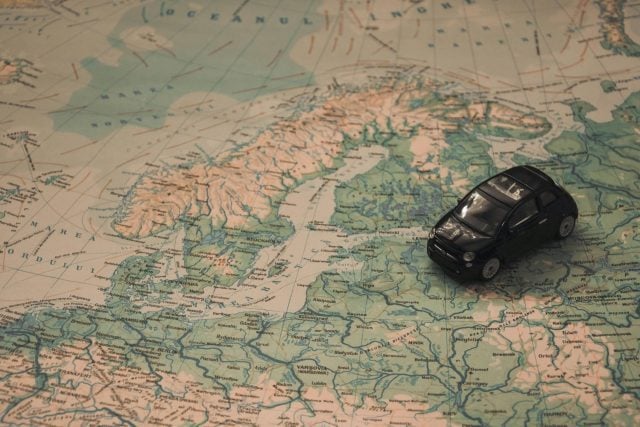 malý model autíčka položený na mape Európy